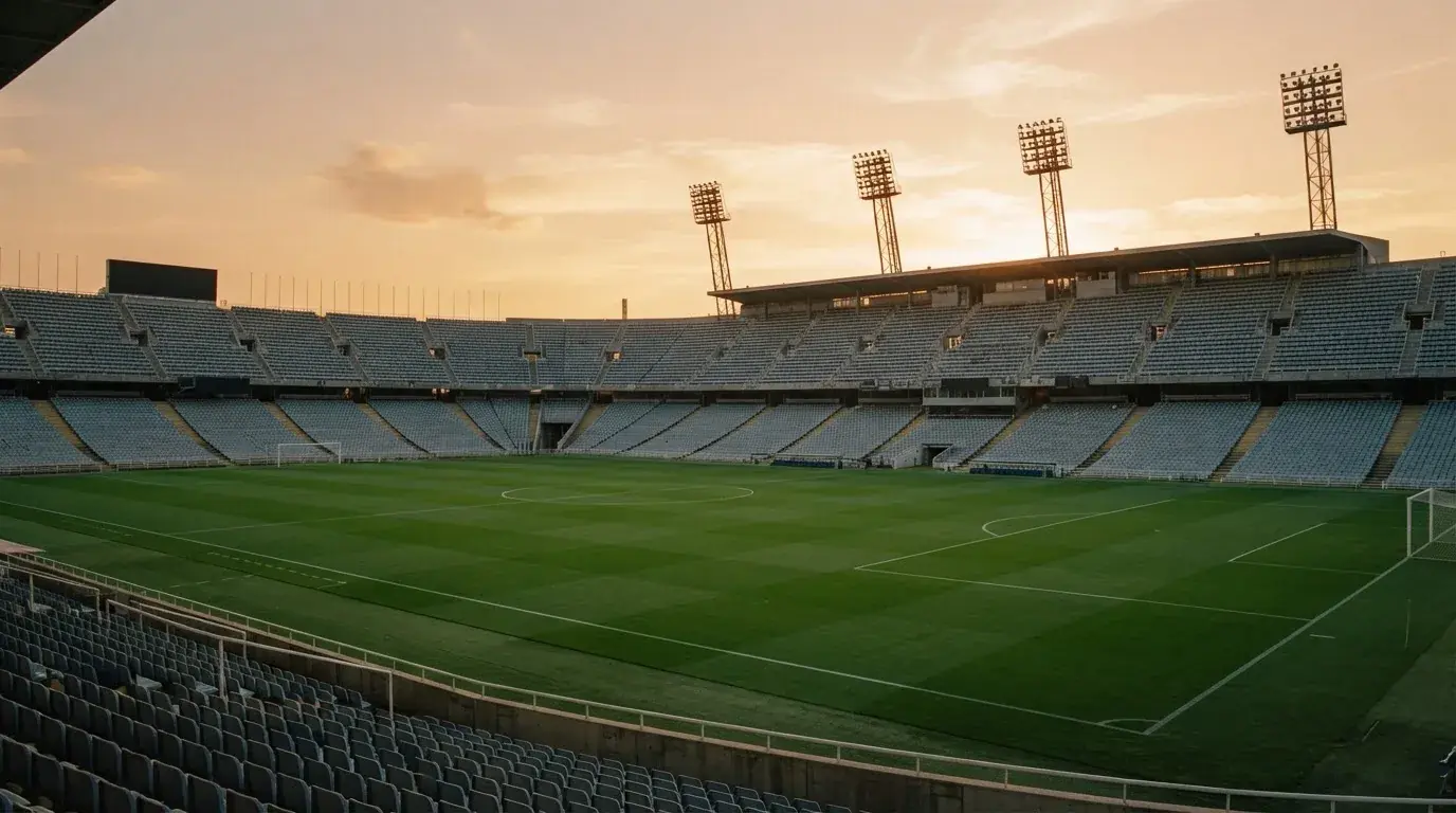 Un estadio de fútbol vacío con torres de iluminación al atardecer