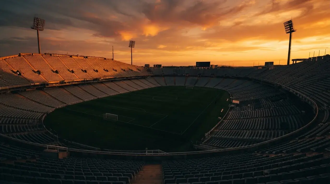 Un estadio de fútbol vacío con torres de iluminación al atardecer