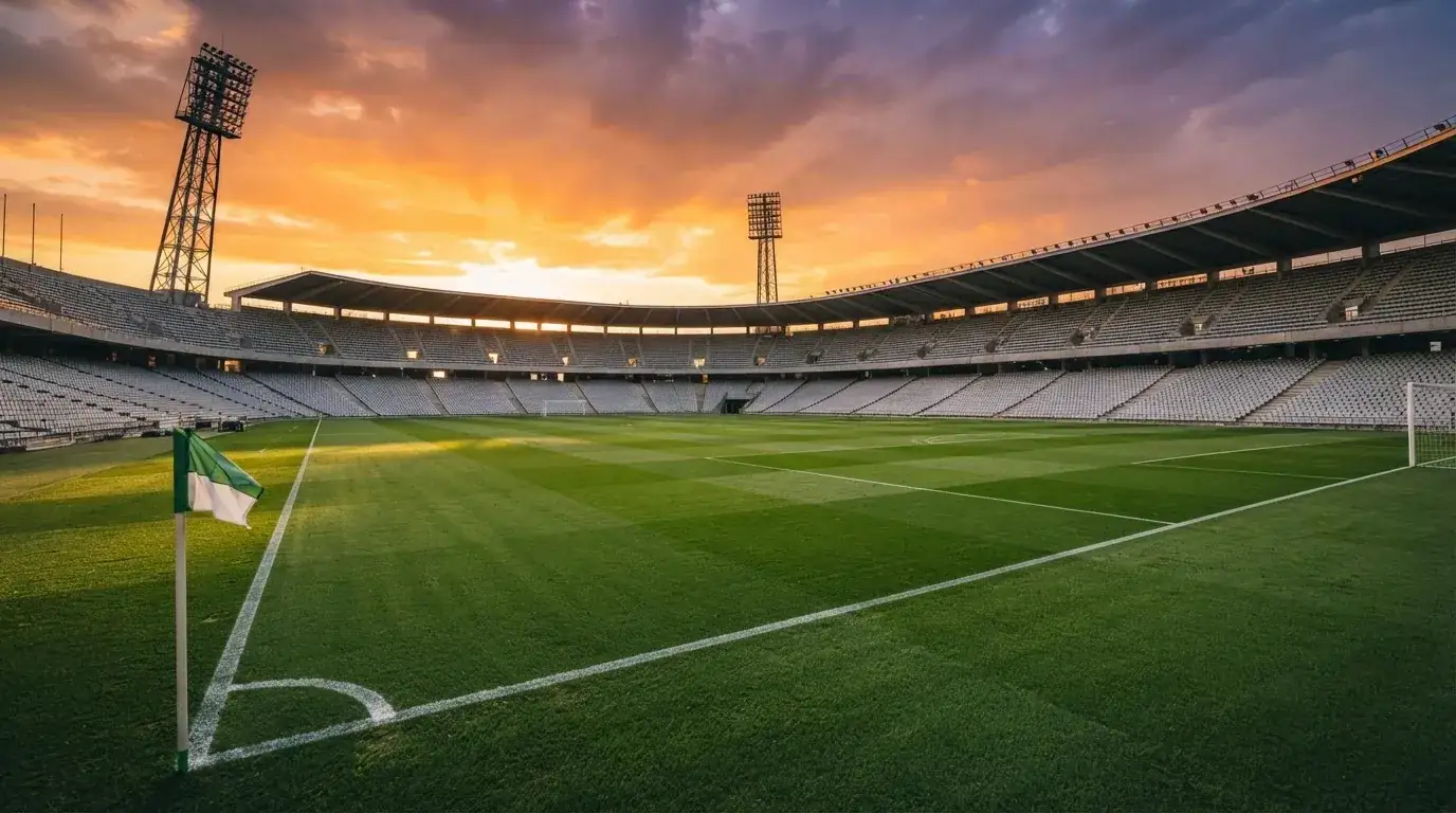 Un estadio de fútbol vacío con torres de iluminación al atardecer