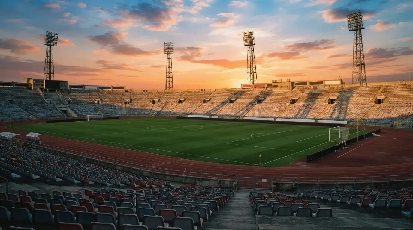 Un estadio de fútbol vacío con torres de iluminación al atardecer