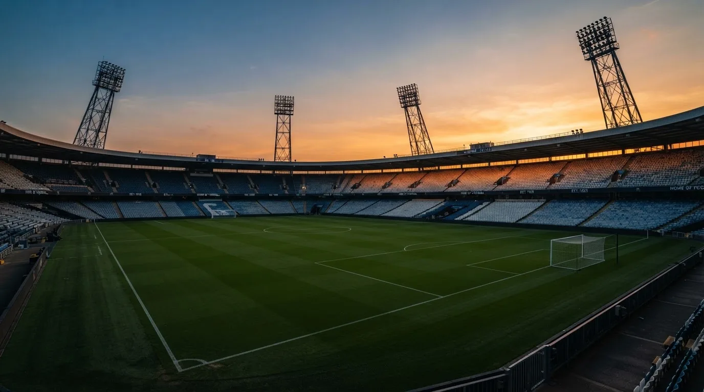 Un estadio de fútbol vacío con torres de iluminación al atardecer
