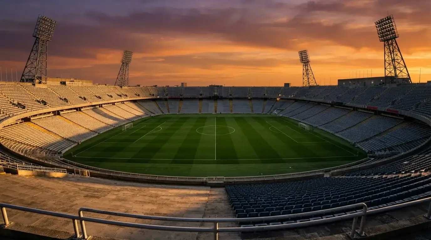 Un estadio de fútbol vacío con torres de iluminación al atardecer