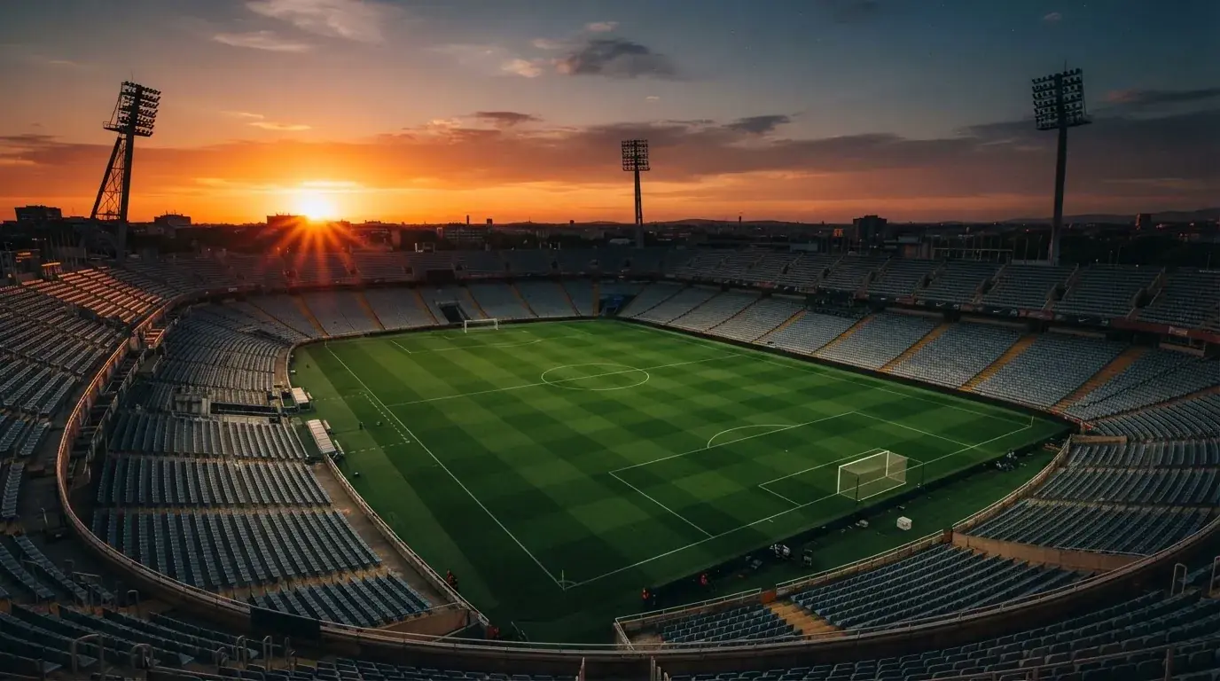Un estadio de fútbol vacío con torres de iluminación al atardecer