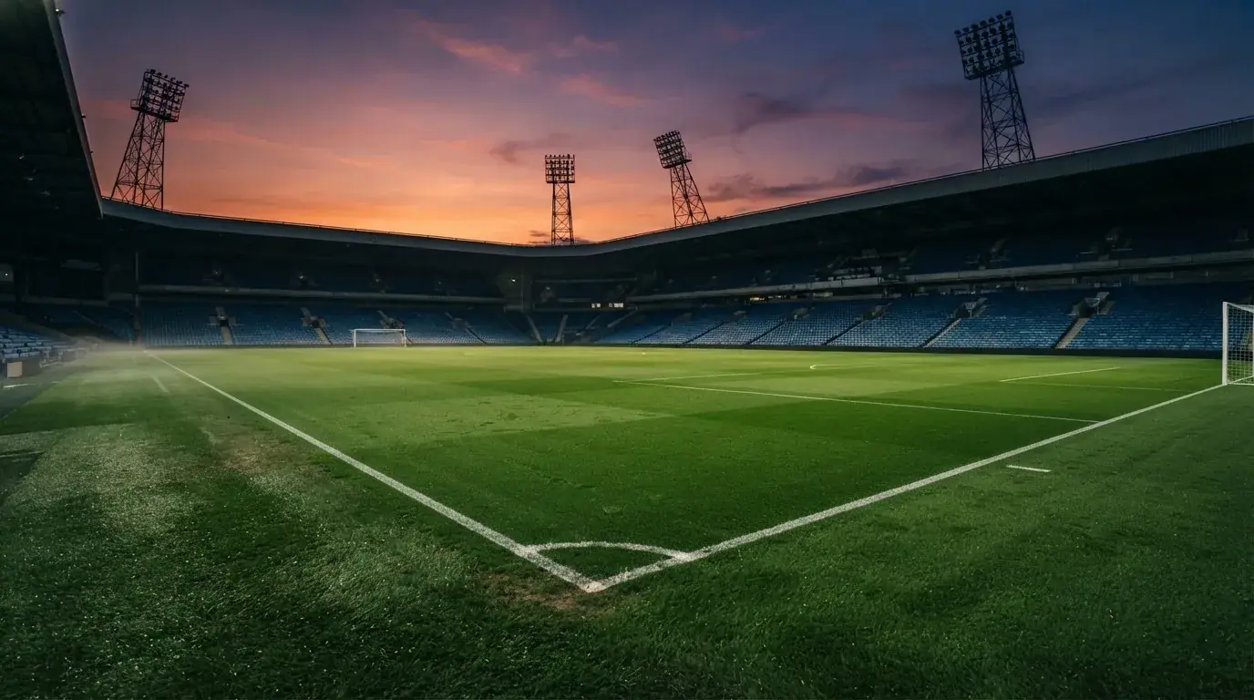 Un estadio de fútbol vacío con torres de iluminación al atardecer