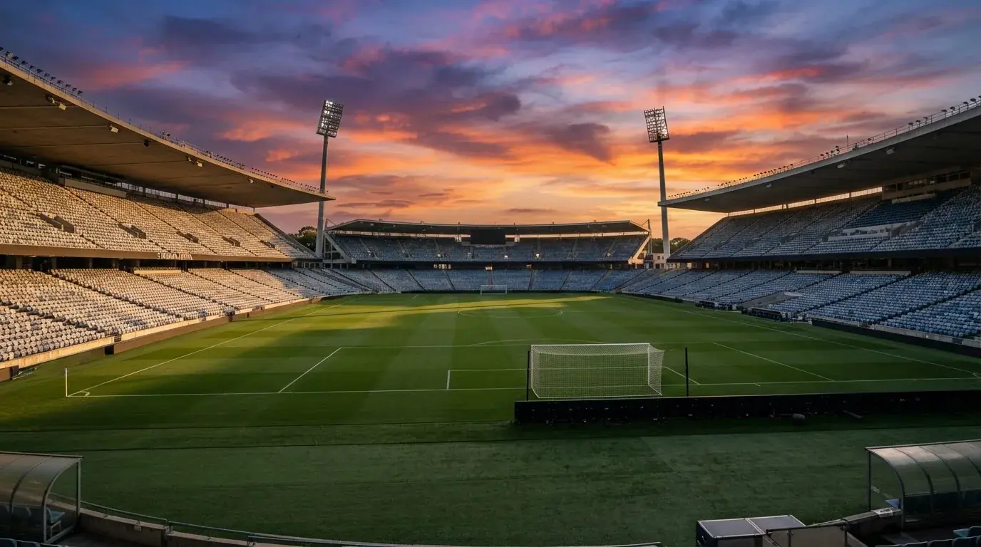 Un estadio de fútbol vacío con torres de iluminación al atardecer