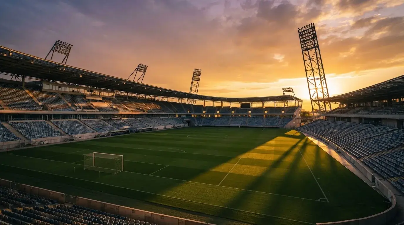 Un estadio de fútbol vacío con torres de iluminación al atardecer