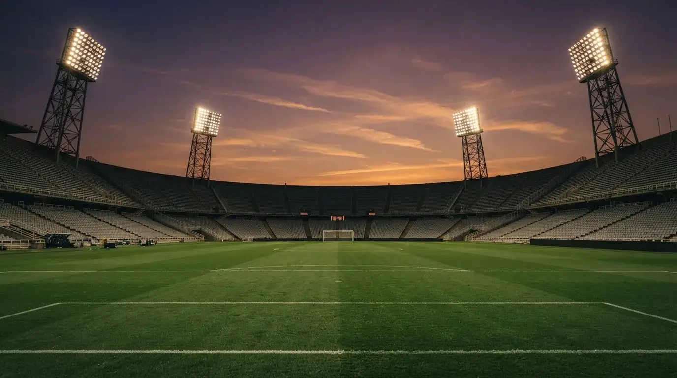 Un estadio de fútbol vacío con torres de iluminación al atardecer