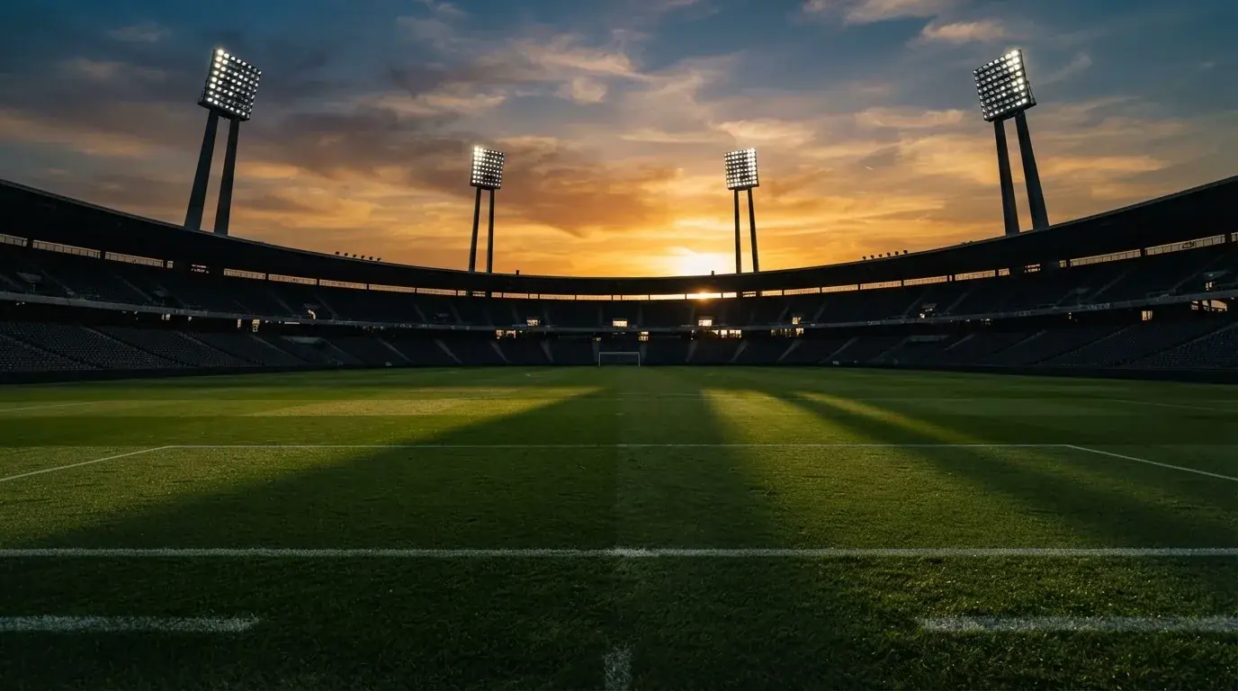 Un estadio de fútbol vacío con torres de iluminación al atardecer