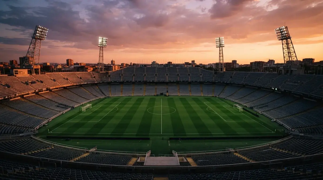 Un estadio de fútbol vacío con torres de iluminación al atardecer