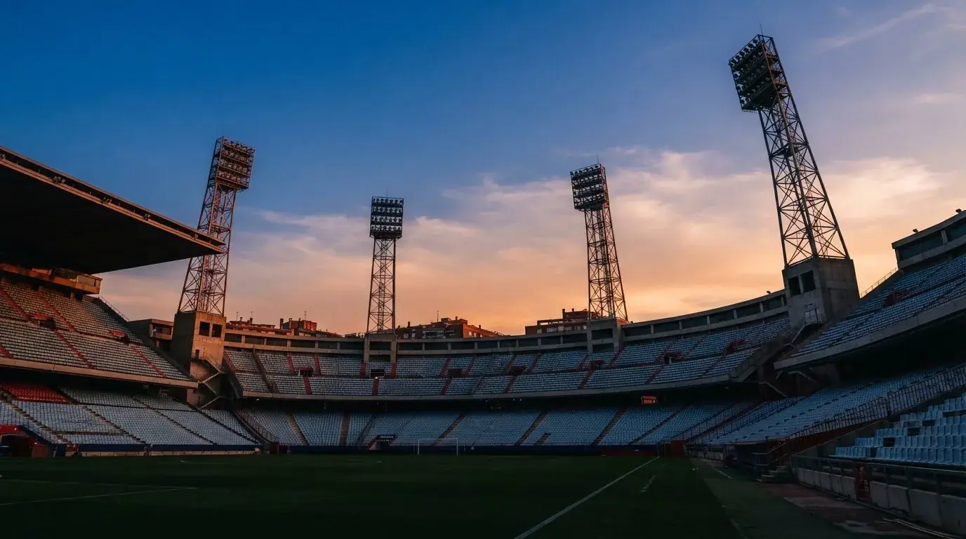 Un estadio de fútbol vacío con torres de iluminación al atardecer